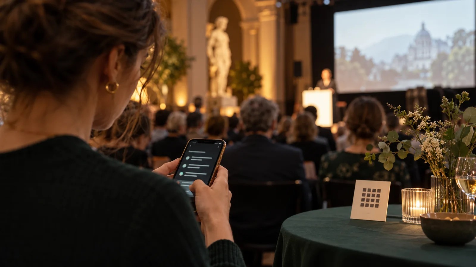 A guest reads a smartphone beside an event welcome desk.